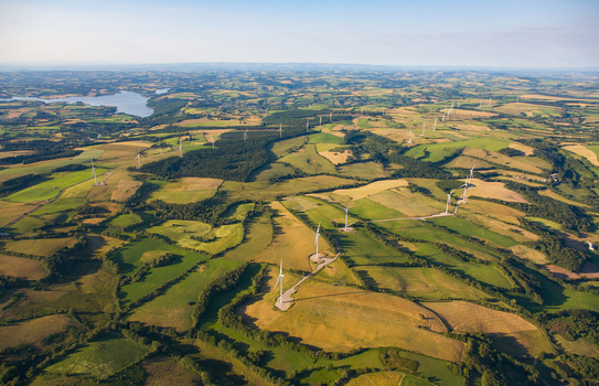 Aerial view of wind turbines dotting the patchwork fields mirrored by the tranquil lake in the distance Salles Curan Occitanie France. Aerial view of wind turbines dotting the patchwork fields mirrored by the tranquil lake in the distance Salles Curan Occitanie France.