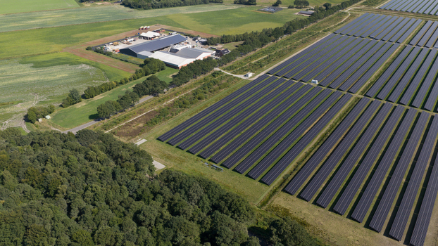 Aerial view of Zonnepark Pekela featuring extensive rows of solar panels situated in green fields next to farm buildings and a forest in Oude Pekela Groningen Netherlands. Aerial view of Zonnepark Pekela featuring extensive rows of solar panels situated in green fields next to farm buildings and a forest in Oude Pekela Groningen Netherlands.