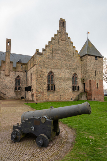 View of Radboud Castle with a historic iron cannon on a carriage in the foreground brick walls and stepped gables Medemblik Noord Holland Netherlands. View of Radboud Castle with a historic iron cannon on a carriage in the foreground brick walls and stepped gables Medemblik Noord Holland Netherlands.
