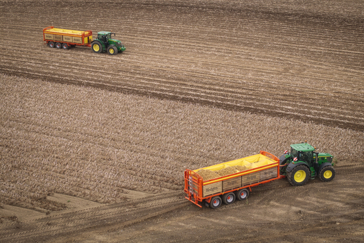 Aerial view of Keogh s Farm with green tractors and orange trailers harvesting potatoes in a vast agricultural field in Oldtown County Dublin Ireland. Aerial view of Keogh s Farm with green tractors and orange trailers harvesting potatoes in a vast agricultural field in Oldtown County Dublin Ireland.