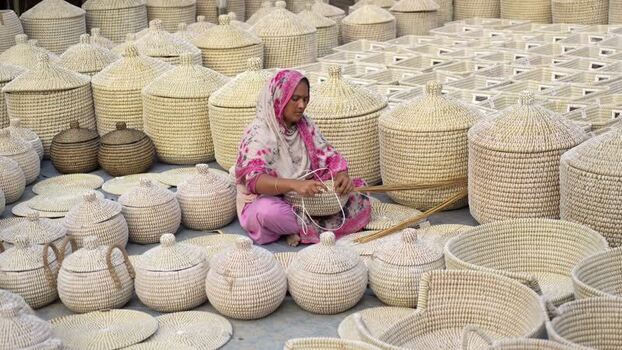 View of a woman weaving traditional baskets in Bogura Bangladesh. View of a woman weaving traditional baskets in Bogura Bangladesh.