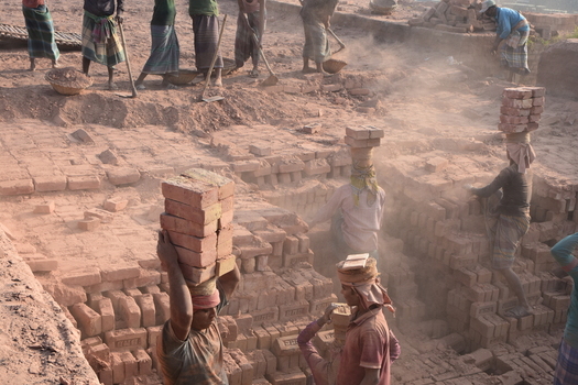 Kushtia District Khulna Division Bangladesh 28 November 2020 View of workers carrying heavy stacks of bricks on their heads in a dusty brick factory. Kushtia District Khulna Division Bangladesh 28 November 2020 View of workers carrying heavy stacks of bricks on their heads in a dusty brick factory.