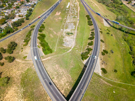 Aerial view of the highway interchange in Brackenfell with vehicles on the multi lane road surrounded by grassy embankments and suburban areas in Cape Town Western Cape South Africa. Aerial view of the highway interchange in Brackenfell with vehicles on the multi lane road surrounded by grassy embankments and suburban areas in Cape Town Western Cape South Africa.