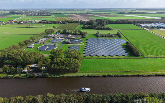Aerial view of a water treatment plant with circular sedimentation tanks and solar panels in the rural landscape near a canal with a boat in Schagerbrug Noord Holland Netherlands. Aerial view of a water treatment plant with circular sedimentation tanks and solar panels in the rural landscape near a canal with a boat in Schagerbrug Noord Holland Netherlands.