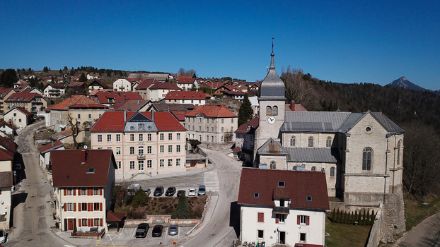 Aerial view of the historic Church of Saint Maurice surrounded by traditional stone houses with red tiled roofs in the village of Jougne Bourgogne Franche Comte France. Aerial view of the historic Church of Saint Maurice surrounded by traditional stone houses with red tiled roofs in the village of Jougne Bourgogne Franche Comte France.