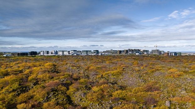 Aerial view of a modern apartment complex situated amidst rugged lava fields and autumn colored vegetation under a cloudy sky in Iceland. Aerial view of a modern apartment complex situated amidst rugged lava fields and autumn colored vegetation under a cloudy sky in Iceland.