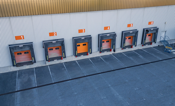 Aerial view of warehouse loading dock doors at a modern logistics center with numbered bays and asphalt parking area in Le Pouzin Auvergne Rhone Alpes France.