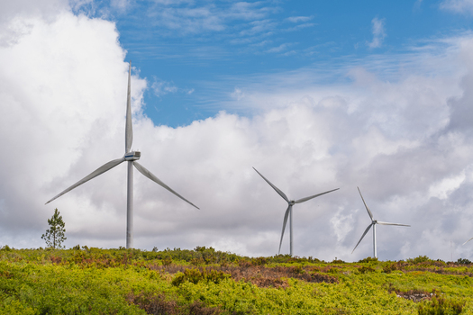 View of wind turbines at Parque Eolico da Serra dos Candeeiros set against a backdrop of rolling green hills and a cloudy blue sky in Rio Maior Santarem Portugal. View of wind turbines at Parque Eolico da Serra dos Candeeiros set against a backdrop of rolling green hills and a cloudy blue sky in Rio Maior Santarem Portugal.