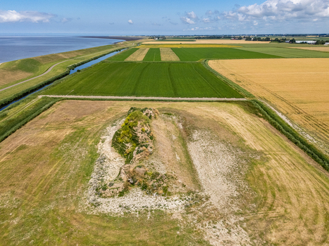Aerial view of the Dijk van een wijf sculpture in a rural landscape with agricultural fields a dike and the Wadden Sea in the distance in Oosterbierum Friesland Netherlands. Aerial view of the Dijk van een wijf sculpture in a rural landscape with agricultural fields a dike and the Wadden Sea in the distance in Oosterbierum Friesland Netherlands.