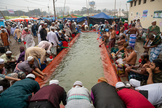 Tongi Bangladesh 31 January 2025 Aerial view of men performing ablution at the Tongi Ijtema Maidan with people gathered around a water trough.