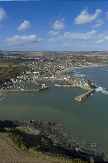 Aerial view of Stonehaven harbor with stone piers and boats surrounded by the coastal town and green hills under a blue sky Stonehaven Scotland United Kingdom. Aerial view of Stonehaven harbor with stone piers and boats surrounded by the coastal town and green hills under a blue sky Stonehaven Scotland United Kingdom.