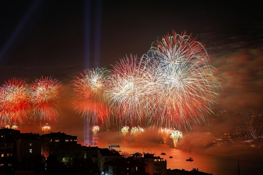 View of vibrant fireworks illuminating the night sky over the Bosphorus strait with silhouettes of boats and city buildings in Istanbul Turkey. View of vibrant fireworks illuminating the night sky over the Bosphorus strait with silhouettes of boats and city buildings in Istanbul Turkey.