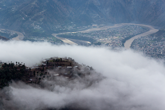 View of a village nestled on a misty hillside overlooking a winding river and distant town creating a serene landscape Pir Chanasi Azad Kashmir Pakistan. View of a village nestled on a misty hillside overlooking a winding river and distant town creating a serene landscape Pir Chanasi Azad Kashmir Pakistan.