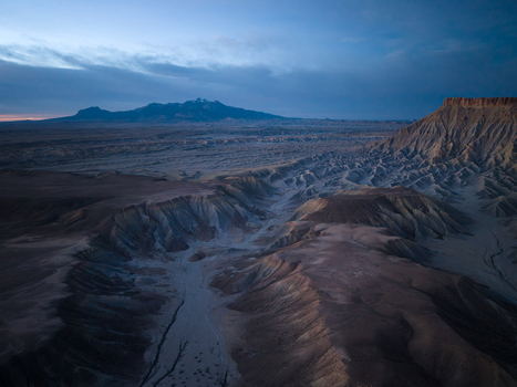 Aerial view of the rugged badlands and eroded desert landscape near Caineville under a soft twilight sky in Caineville Utah United States. Aerial view of the rugged badlands and eroded desert landscape near Caineville under a soft twilight sky in Caineville Utah United States.