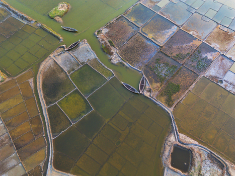 Aerial view of geometric salt pans and aquaculture ponds with small wooden boats in narrow water channels Moheskhali Upazila Chittagong Division Bangladesh. Aerial view of geometric salt pans and aquaculture ponds with small wooden boats in narrow water channels Moheskhali Upazila Chittagong Division Bangladesh.