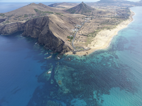 Aerial view of Ponta da Calheta featuring rugged cliffs sandy beach turquoise waters and coastal road in Porto Santo Madeira Portugal. Aerial view of Ponta da Calheta featuring rugged cliffs sandy beach turquoise waters and coastal road in Porto Santo Madeira Portugal.