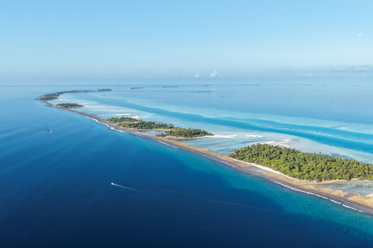 Aerial view of lush tropical islands with green palm trees and turquoise coral reefs surrounded by the deep blue ocean under a clear sky near Vaanee Dhaalu Atoll Maldives. Aerial view of lush tropical islands with green palm trees and turquoise coral reefs surrounded by the deep blue ocean under a clear sky near Vaanee Dhaalu Atoll Maldives.