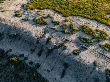Aerial view of the dry eroded flat landscape with sparse green vegetation and visible tire tracks in Hay New South Wales Australia.