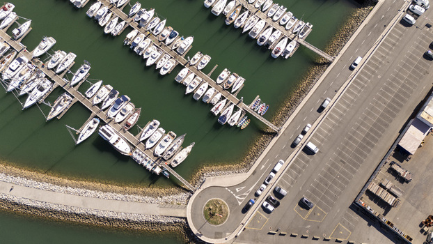 Aerial view of the marina in Zumaia with numerous boats docked at piers a parking lot with cars and a stone breakwater in Zumaia Basque Country Spain.