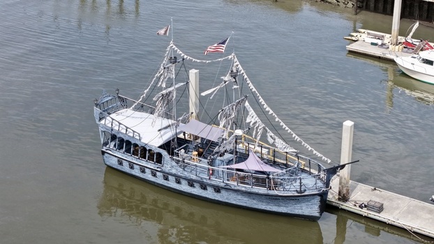 Aerial view of a whimsical pirate ship replica with tattered sails and festive bunting docked at a pier Fernandina Beach Florida United States. Aerial view of a whimsical pirate ship replica with tattered sails and festive bunting docked at a pier Fernandina Beach Florida United States.