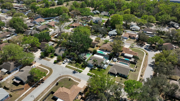 Aerial view of a suburban residential neighborhood featuring single family homes with swimming pools paved streets and lush green trees in Brandon Florida United States.