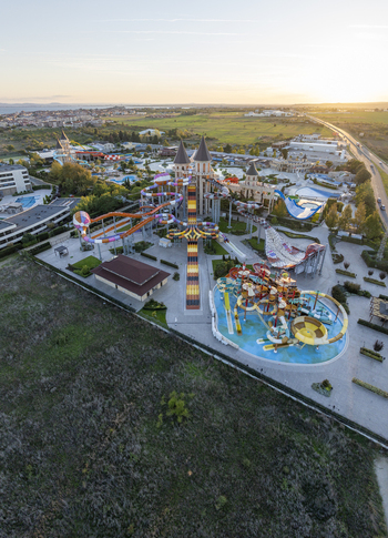 Aerial view of a large water park featuring colorful slides pools and castle themed towers under the warm glow of the sunset in Bulgaria. Aerial view of a large water park featuring colorful slides pools and castle themed towers under the warm glow of the sunset in Bulgaria.