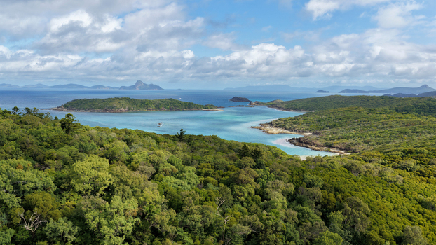 Aerial view of Chance Bay with turquoise waters and lush green forest on the islands in the Whitsundays Queensland Australia. Aerial view of Chance Bay with turquoise waters and lush green forest on the islands in the Whitsundays Queensland Australia.