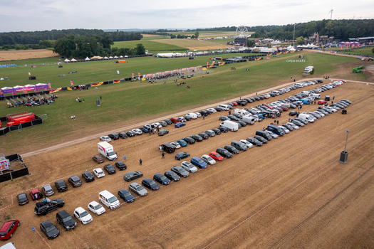 Herzogenaurach Germany 25 July 2025 Aerial view of Open Beatz Festival featuring a large parking area with cars green fields and a Ferris wheel under an overcast sky. Herzogenaurach Germany 25 July 2025 Aerial view of Open Beatz Festival featuring a large parking area with cars green fields and a Ferris wheel under an overcast sky.