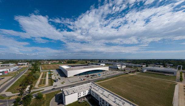 Opole Poland 09 September 2026 Aerial view of Itaka Arena surrounded by modern buildings parking areas and green spaces under a blue sky with scattered clouds. Opole Poland 09 September 2026 Aerial view of Itaka Arena surrounded by modern buildings parking areas and green spaces under a blue sky with scattered clouds.