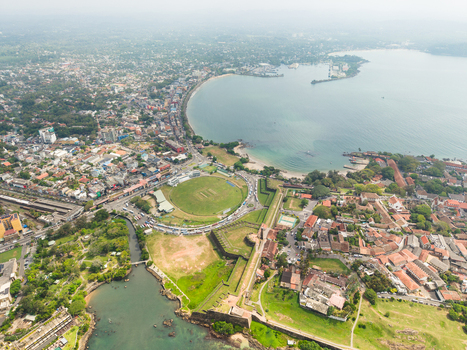 Aerial view of the historic Galle Fort and the Galle International Stadium cricket ground overlooking the turquoise bay and coastal rooftops in Galle Southern Province Sri Lanka. Aerial view of the historic Galle Fort and the Galle International Stadium cricket ground overlooking the turquoise bay and coastal rooftops in Galle Southern Province Sri Lanka.