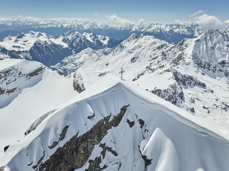 Aerial view of the snow covered summit of Valmalenco featuring a prominent summit cross surrounded by jagged alpine peaks under a clear blue sky Lombardia Italy. Aerial view of the snow covered summit of Valmalenco featuring a prominent summit cross surrounded by jagged alpine peaks under a clear blue sky Lombardia Italy.