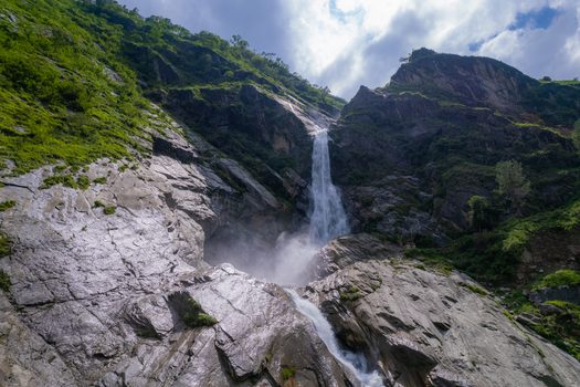 Aerial view of a powerful waterfall cascading down steep rocky cliffs surrounded by lush green vegetation Nepal.