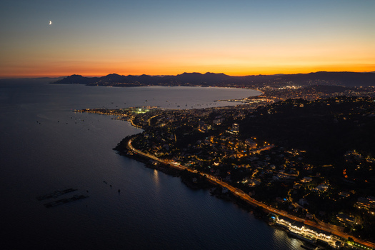 Aerial view of the coastal town of Antibes at twilight with city lights illuminating the shoreline the Mediterranean Sea and a crescent moon in the sky Antibes Provence Alpes Cote d Azur France. Aerial view of the coastal town of Antibes at twilight with city lights illuminating the shoreline the Mediterranean Sea and a crescent moon in the sky Antibes Provence Alpes Cote d Azur France.