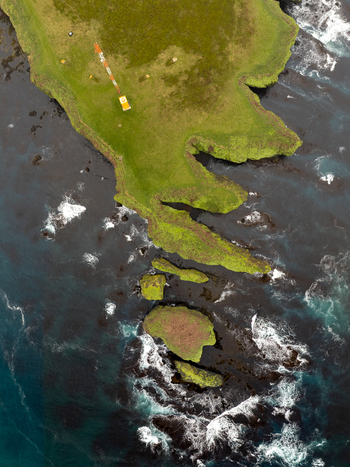 Aerial view of the rugged Tjornes peninsula coastline with green grassy cliffs rocky outcrops and crashing waves in the North Atlantic Ocean Tjorneshreppur Iceland. Aerial view of the rugged Tjornes peninsula coastline with green grassy cliffs rocky outcrops and crashing waves in the North Atlantic Ocean Tjorneshreppur Iceland.