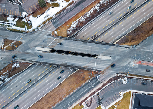 Aerial view of a highway interchange with cars driving on asphalt roads patches of snow on the ground and surrounding urban infrastructure in Southfield Michigan United States.