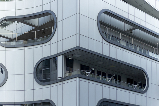 View of a modern building facade featuring unique rounded balcony openings and sleek grey panels in Taipei City Taiwan. View of a modern building facade featuring unique rounded balcony openings and sleek grey panels in Taipei City Taiwan.
