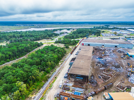 Wilmington North Carolina United States 18 September 2026 Aerial view of an industrial scrap yard with metal piles railway tracks and warehouses near a forest and river.