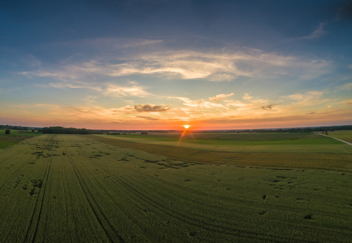 Aerial view of vast agricultural fields during a golden sunset with a vibrant sky over the rural landscape of Latvia. Aerial view of vast agricultural fields during a golden sunset with a vibrant sky over the rural landscape of Latvia.