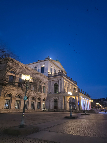 Hanover Germany 30 March 2026 View of the illuminated Hanover State Opera at twilight with street lamps and a clear blue sky.