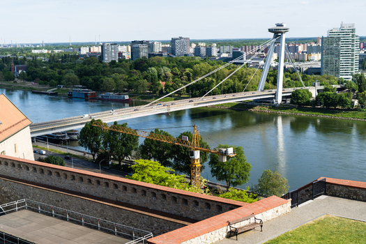 View of the Most SNP bridge crossing the Danube river with the city skyline and lush greenery in Bratislava Bratislava Region Slovakia. View of the Most SNP bridge crossing the Danube river with the city skyline and lush greenery in Bratislava Bratislava Region Slovakia.