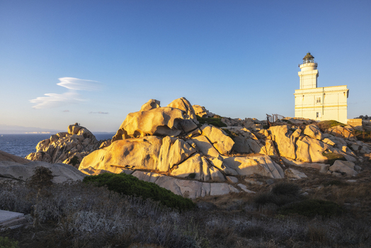 View of the Capo Testa Lighthouse and weathered granite rock formations during golden hour Capo Testa Sardegna Italy. View of the Capo Testa Lighthouse and weathered granite rock formations during golden hour Capo Testa Sardegna Italy.