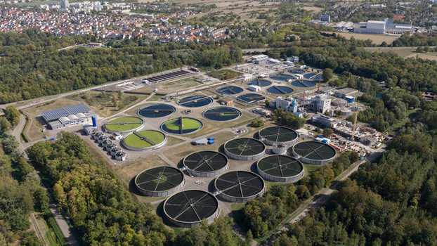 Aerial view of Klarwerk Karlsruhe wastewater treatment plant with circular sedimentation tanks and industrial infrastructure surrounded by forest in Karlsruhe Baden Wurttemberg Germany.