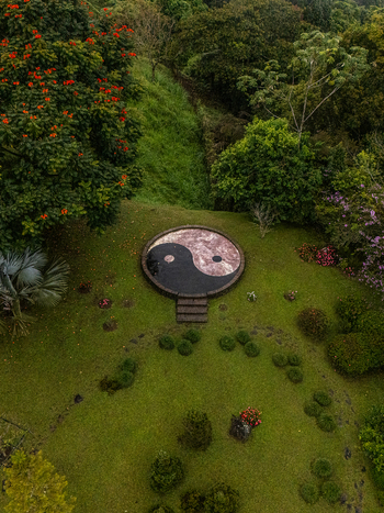 Aerial view of a large Yin Yang symbol set in a lush tropical garden surrounded by vibrant flowering trees and dense green foliage Cinchona Alajuela Province Costa Rica. Aerial view of a large Yin Yang symbol set in a lush tropical garden surrounded by vibrant flowering trees and dense green foliage Cinchona Alajuela Province Costa Rica.