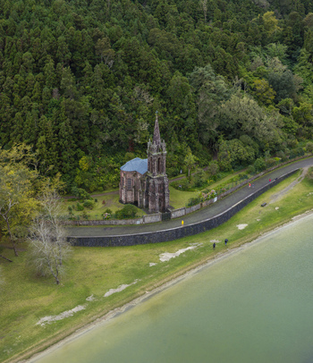 Aerial view of the neo Gothic Ermida de Nossa Senhora das Vitorias chapel nestled in lush forest beside the lake in Furnas Acores Portugal. Aerial view of the neo Gothic Ermida de Nossa Senhora das Vitorias chapel nestled in lush forest beside the lake in Furnas Acores Portugal.