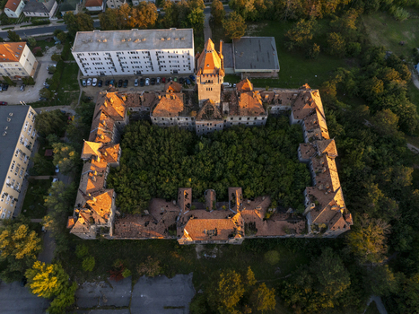 Aerial view of the abandoned Hajmasker Barracks with its overgrown central courtyard and historic orange tiled roofs illuminated by golden hour light in Hajmasker Hungary. Aerial view of the abandoned Hajmasker Barracks with its overgrown central courtyard and historic orange tiled roofs illuminated by golden hour light in Hajmasker Hungary.