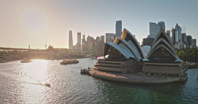 Aerial view of Sydney Opera House with the city skyline in the background boats on the water and golden hour light in Sydney New South Wales Australia. Aerial view of Sydney Opera House with the city skyline in the background boats on the water and golden hour light in Sydney New South Wales Australia.