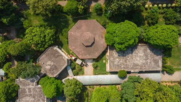 Lahore Punjab Pakistan 08 September 2026 Aerial view of a government office complex featuring an octagonal building surrounded by lush green trees paved pathways and manicured lawns.