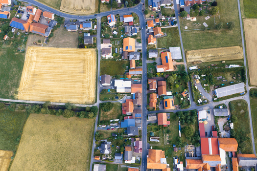 Aerial view of a rural village with houses featuring orange rooftops solar panels and surrounding agricultural fields in Burghaun Hessen Germany. Aerial view of a rural village with houses featuring orange rooftops solar panels and surrounding agricultural fields in Burghaun Hessen Germany.