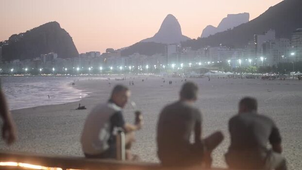 View of people at Copacabana Beach at dusk in Brazil.