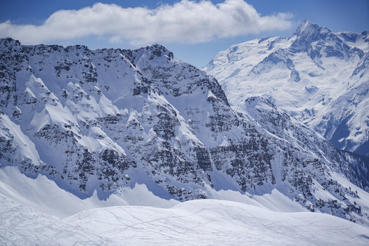 Aerial view of La Rosiere ski resort area featuring snow capped mountain peaks rugged ridges and deep snow under a clear blue sky in Montvalezan Auvergne Rhone Alpes France.